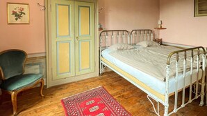 Um quarto com uma cama, uma cadeira, um guarda-roupa e um tapete vermelho.