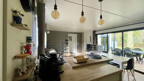 Een moderne keuken met een houten aanrechtblad, hangende lampen en uitzicht op het landschap door grote ramen.