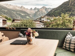 A table with a laptop, a vase with flowers, and a glass on a balcony overlooking a mountainous landscape with houses. - Apart  Bieles NEU by Interhome (Kauns)