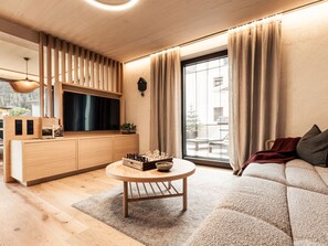 A modern living room with a wooden TV stand, a round coffee table, and a sofa. - Apart  Bieles NEU by Interhome (Kauns)