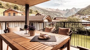 A wooden table with a black mat and a woven basket on a balcony with a mountain view. - Apart  Bieles NEU by Interhome (Kauns)