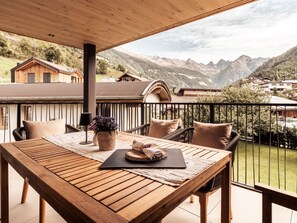 A wooden table with a black mat and a woven basket on a balcony with a mountain view. - Apart  Bieles NEU by Interhome (Kauns)