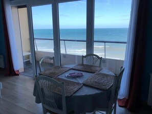 Een eetruimte met een tafel voor vier personen, met uitzicht op een strand.
