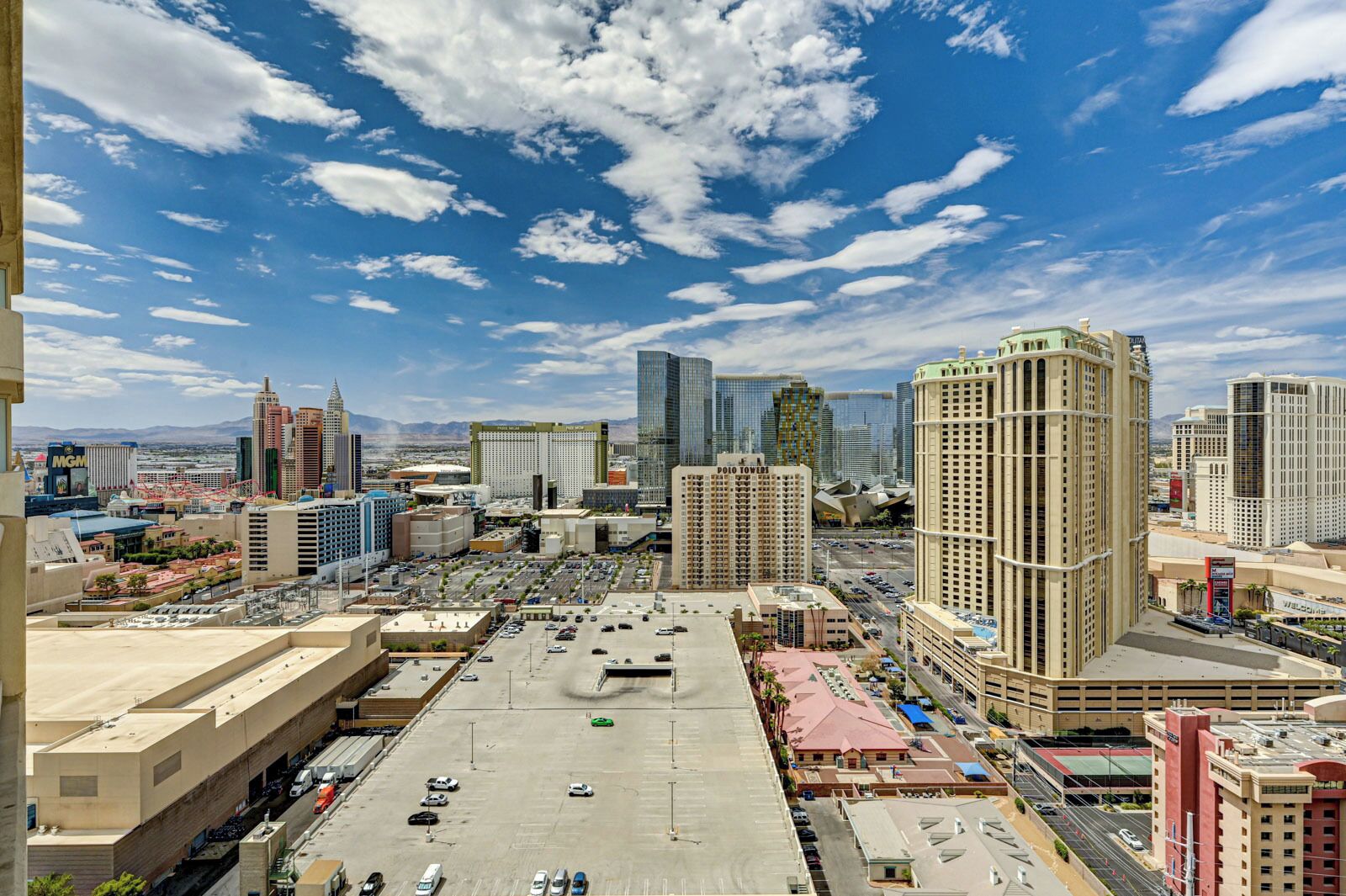 A cityscape with a large parking lot, high-rise buildings, and a clear sky.