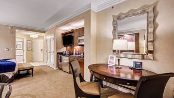 A hotel room with a dining area, a kitchen, and a large mirror.