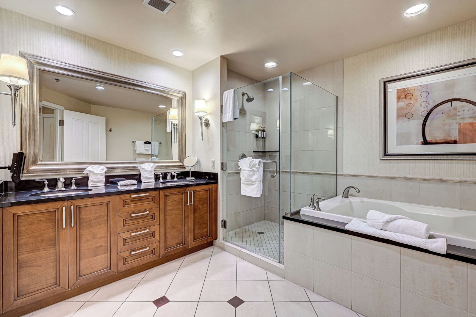 A modern bathroom with a large mirror, wooden vanity, a glass-enclosed shower, and a bathtub.