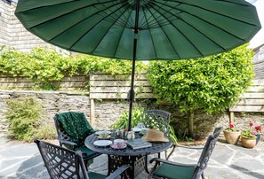Une table ronde avec des chaises, un parasol et du mobilier d’extérieur.