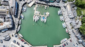 Una marina con barche ormeggiate, una passeggiata pedonale e un’area di parcheggio.