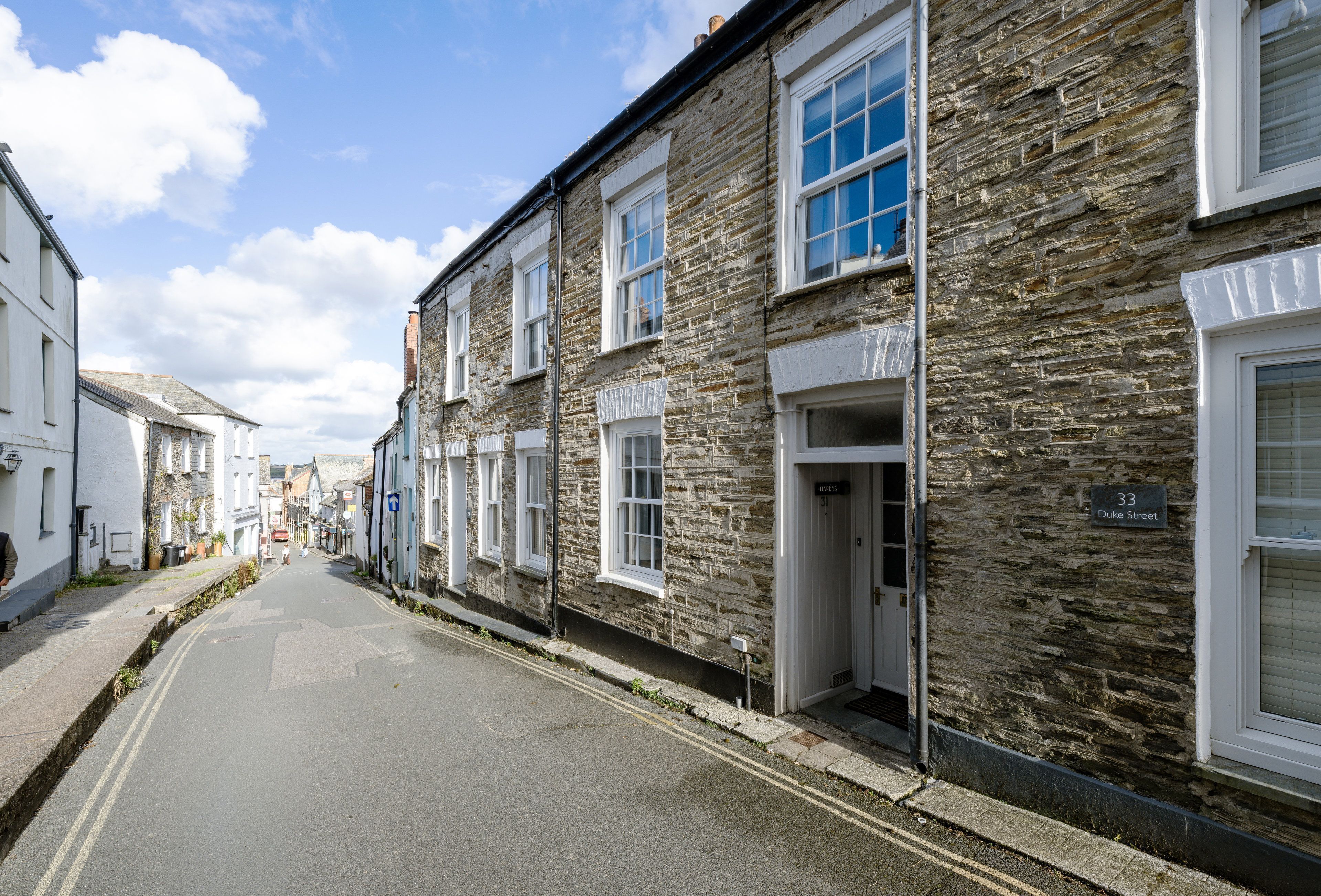 A narrow street lined with stone buildings, each with a distinct entrance and a sign above the door.
