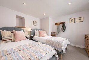 Une chambre d’hôtel avec deux lits, une petite table avec une lampe, un miroir et une commode en bois.