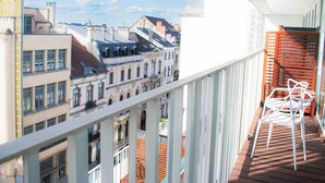 Un balcon avec des balustrades blanches, une terrasse en bois et des chaises blanches.