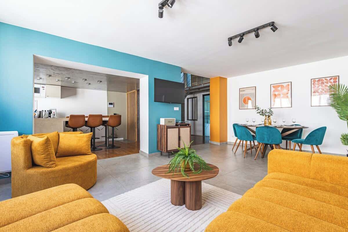 A modern living room with a sofa, coffee table, and dining area with chairs and a table.