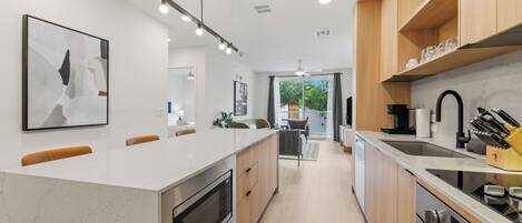 A modern kitchen with a central island, built-in oven, and stainless steel appliances.
