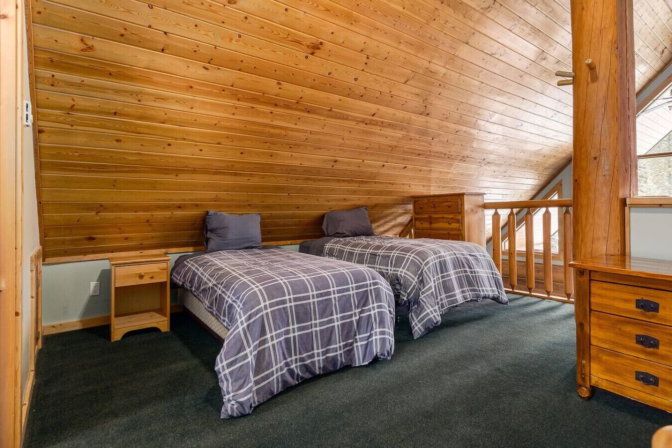 A wooden-paneled room with two beds, a small dresser, and a window with a view.
