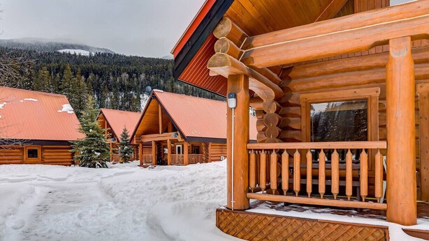 A log cabin with a porch and a snow-covered landscape.