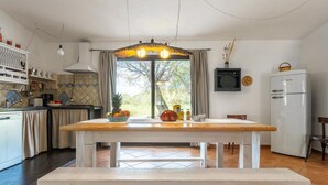 Una cucina con un tavolo in legno, una panca e vista sull'esterno attraverso una finestra.