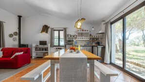 Un soggiorno moderno con un divano rosso, un tavolo da pranzo in legno con panche, una cucina con una grande finestra e un camino.