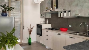 A modern kitchen with a built-in oven, a gas stove, and a stainless steel sink. There are cabinets with glass doors and a red bowl on the countertop. - Beautiful home in Ispica with WiFi (Ispica)