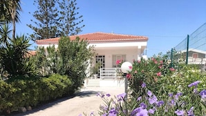 A white building with a red-tiled roof, surrounded by greenery and purple flowers. - Beautiful home in Ispica with WiFi (Ispica)