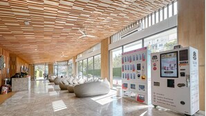 A modern lobby with a wooden ceiling, seating areas, and vending machines. - two-bedroom Beachfront at Veranda Residence (Sattahip)