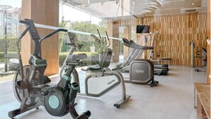 A gym with stationary bikes, treadmills, and a TV screen. - two-bedroom Beachfront at Veranda Residence (Sattahip)