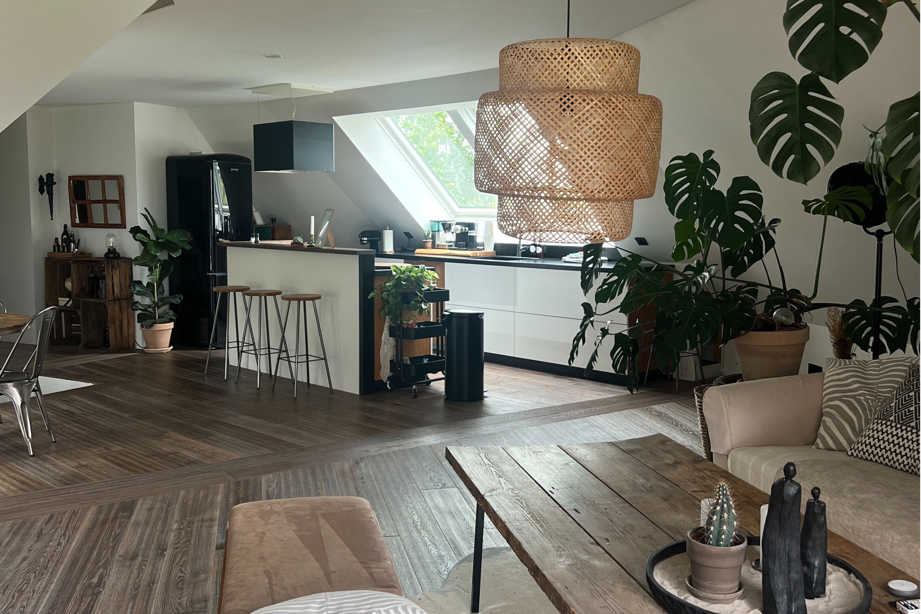 Eine moderne Küche mit einer zentralen Kochinsel, Holzboden und einem großen Fenster für natürliches Licht.