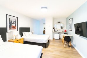 Een moderne hotelkamer met een bed, nachtkastje, lamp en een bureau met stoel.
