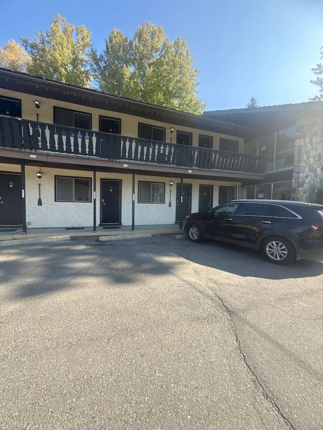 A two-story motel with a black car parked in the driveway.
