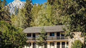 Un bâtiment à deux étages doté d’une façade en pierre, de nombreuses fenêtres et d’un balcon.