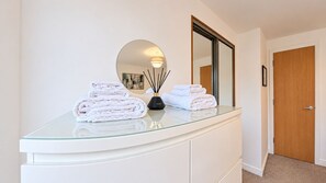A bathroom vanity with a glass top, a mirror, and two rolled towels. - Stormont - Stunning 2 King Bedroom Apartment with Patio (Castlereagh)