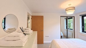 Un dormitorio moderno con una cama grande, un espejo redondo y una puerta de madera.