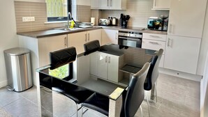 Een moderne keuken met een eethoek, roestvrijstalen apparatuur en een raam dat voor natuurlijk licht zorgt.