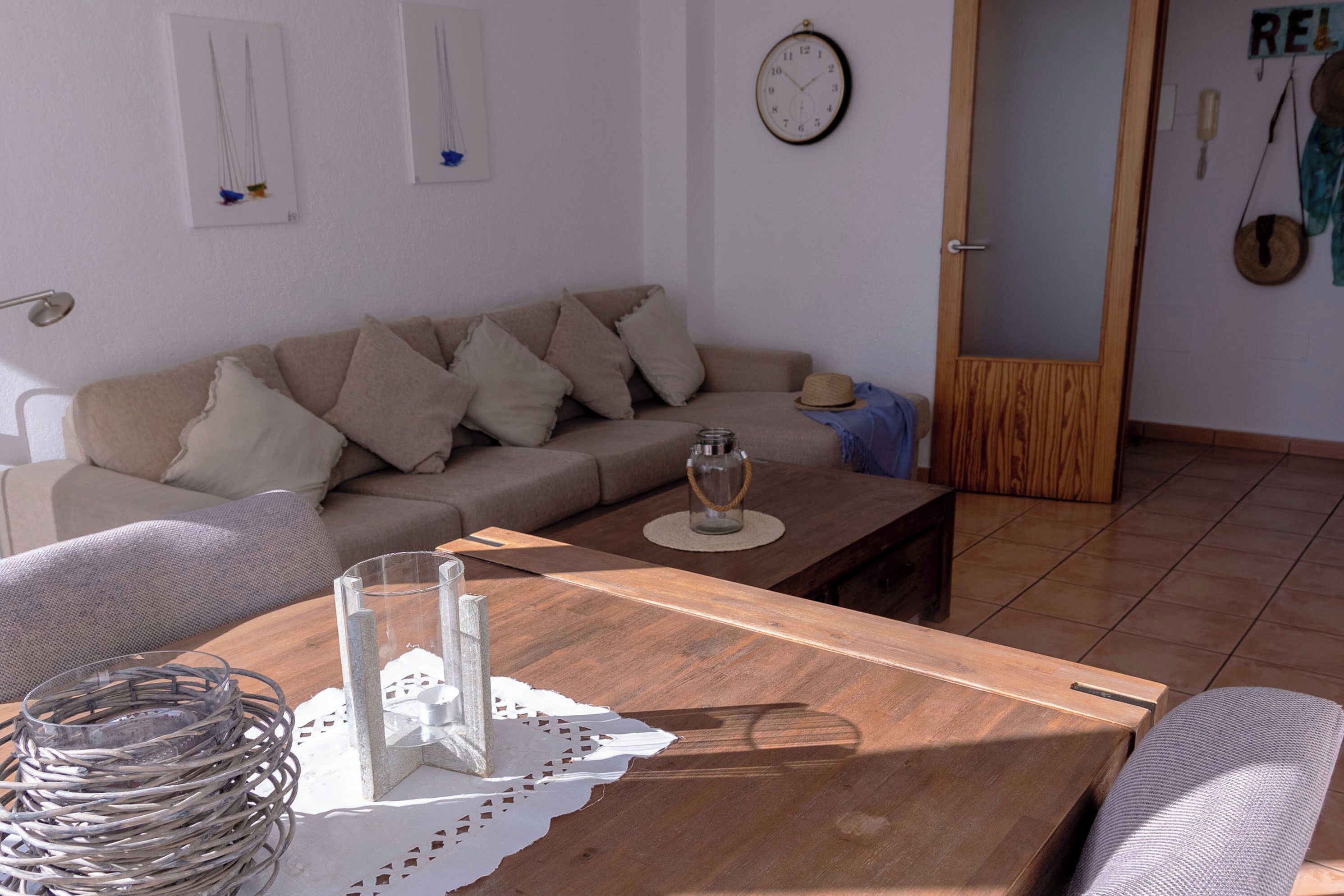 A living room with a wooden coffee table, a beige sofa, and a clock on the wall.