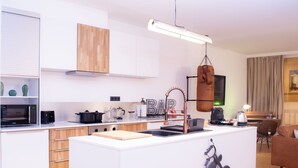 A modern kitchen with a central island, a microwave, a coffee machine, and a hanging punching bag. - "Industrial Sanctum" by Interhome (Brussels)
