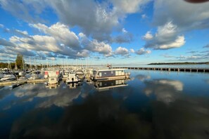Un port de plaisance avec des bateaux amarrés, une jetée s’avançant dans l’eau et un ciel calme parsemé de nuages.