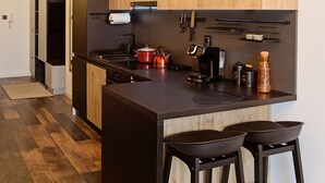 A modern kitchen with a central island, wooden cabinets, and black bar stools.