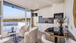 Ein modernes Interieur mit Essbereich, Küche und großen Fenstern mit Blick auf ein Gewässer.