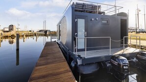 Ein modernes Boot mit Holzboden, einer überdachten Sitzecke und zwei Außenbordmotoren von Mercury.