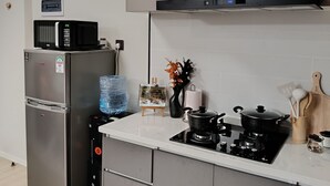 Ett modernt kök med ett kylskåp i rostfritt stål, en mikrovågsugn, en gasspis och en vattenkylare.