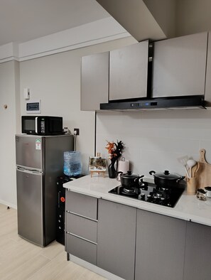 Eine moderne Küche mit einem Edelstahlkühlschrank, einer Mikrowelle, einem Gasherd und einem Wasserspender.