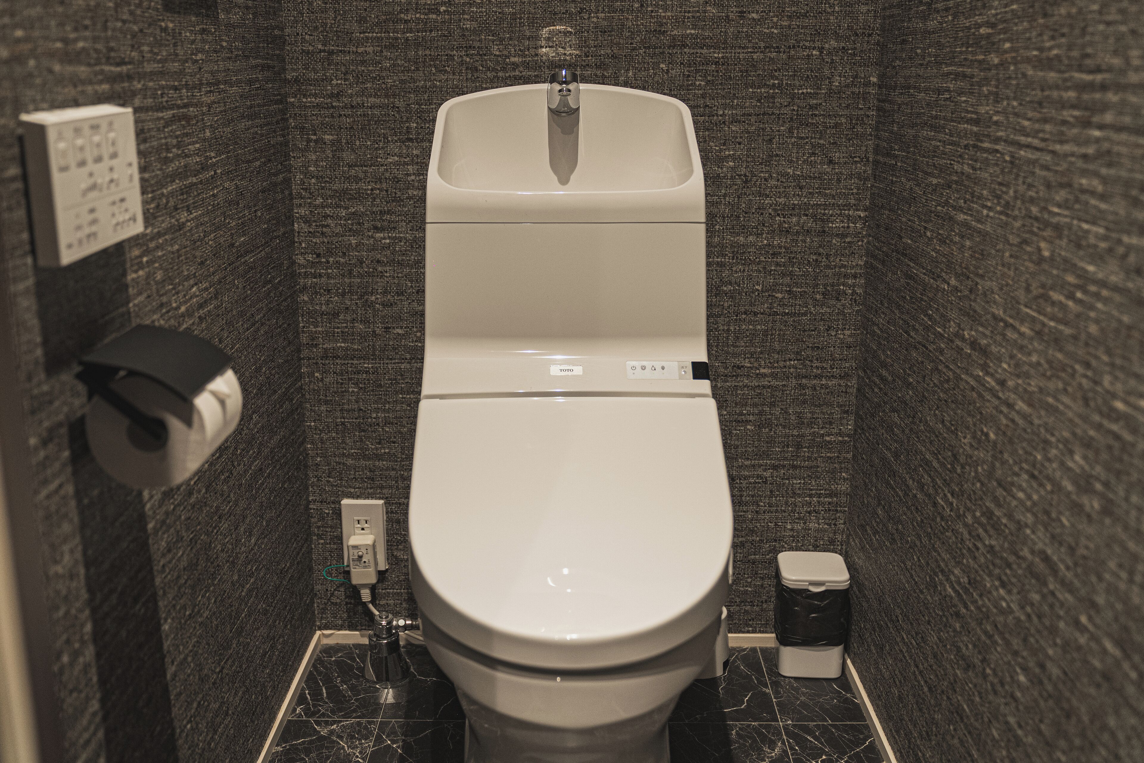 Un bagno moderno e funzionale, con il water, un asciugamani ad aria e un cestino.