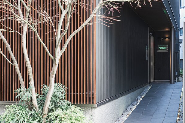 A modern building with a metal facade and a pathway leading to a door marked "THELOFTIN NAGASAKI". - THE LOFT INN NAGASAKI (Nagasaki)