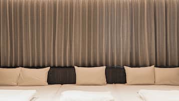Una habitación de hotel con una cama grande, ropa de cama color beige y un telón de fondo de cortina.