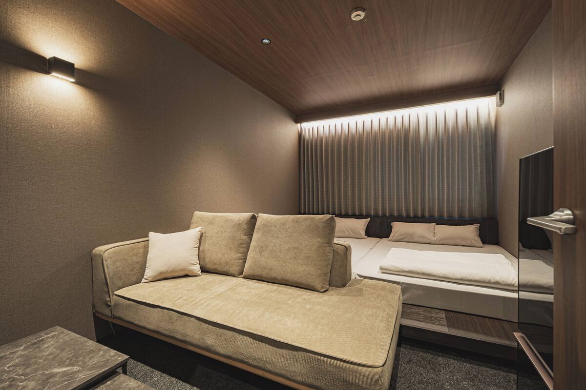 Une chambre d’hôtel moderne équipée d’un canapé, d’un lit, d’une table de chevet et d’un miroir.