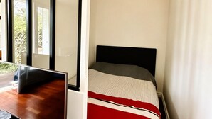 A compact bedroom with a bed, a desk, and a large window. - Exceptional apartment with private garden (Neuilly-sur-Seine)