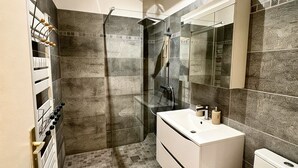 A modern bathroom with a glass-enclosed shower, a white vanity, and a toilet. - Exceptional apartment with private garden (Neuilly-sur-Seine)