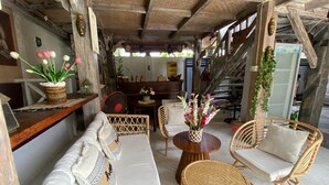A rustic wooden interior with a sofa, wicker chairs, and a round table. - Wooden Cabin in Jimbaran (Jimbaran)