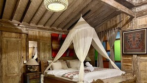 A rustic bedroom with a four-poster canopy bed, wooden walls, and a traditional lamp. - Wooden Cabin in Jimbaran (Jimbaran)