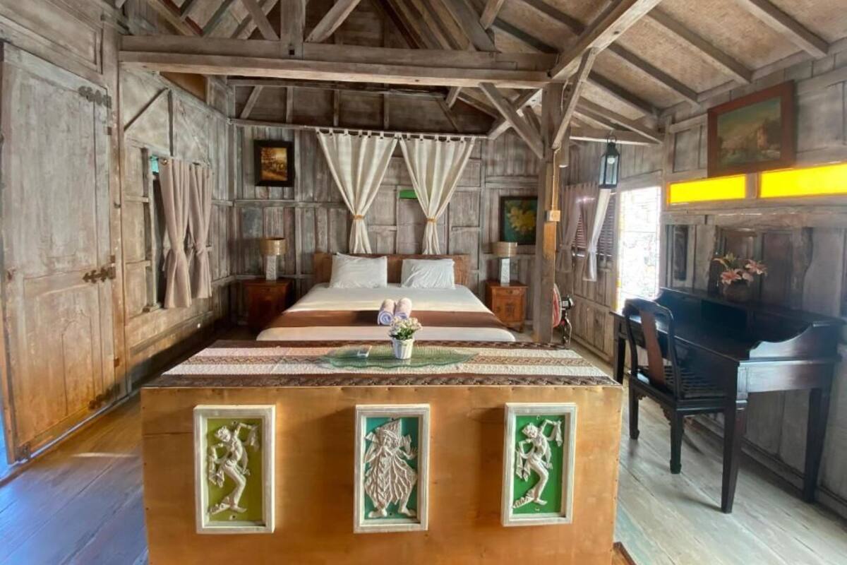 Une pièce rustique en bois, avec un lit, des rideaux, un piano et des panneaux décoratifs.