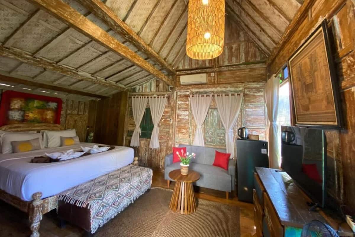 Une chambre rustique avec un lit, un canapé et une petite table sur laquelle est posé un vase.